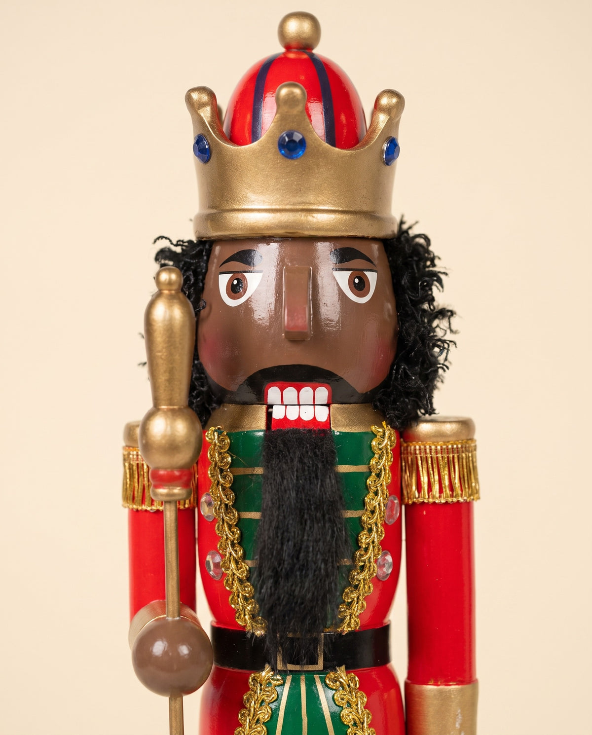 Close-up of the Mahogany King nutcracker's face with deep brown skin, natural curls and full beard